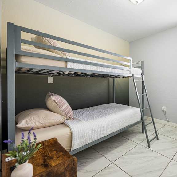 a room with a bunk bed, a chair, and a small table.