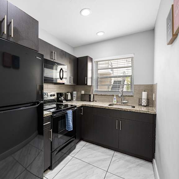 a black refrigerator is in a kitchen with white tile flooring.