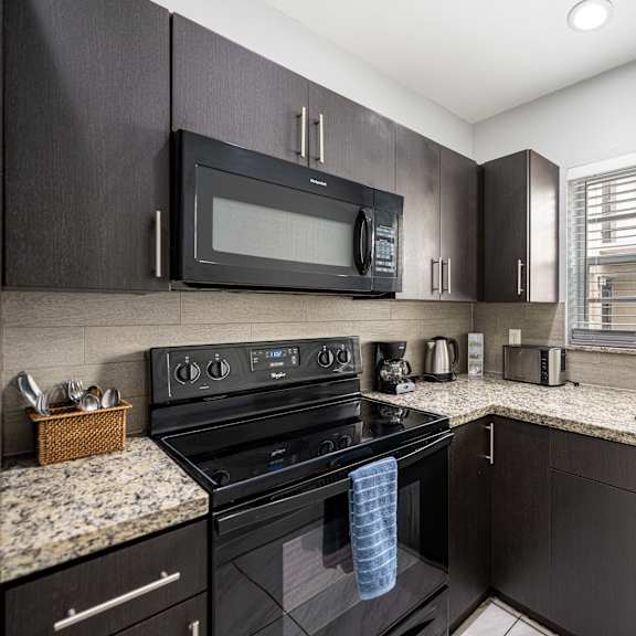 a black kitchen with granite countertops and a window.