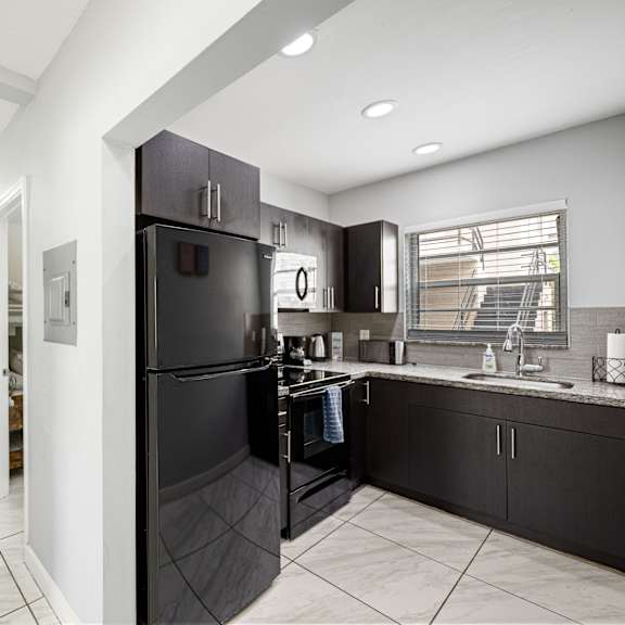 a black refrigerator is in a kitchen with white walls.