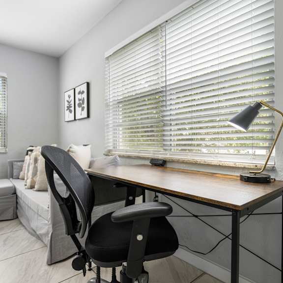 a black chair is in front of a desk with a laptop on it.