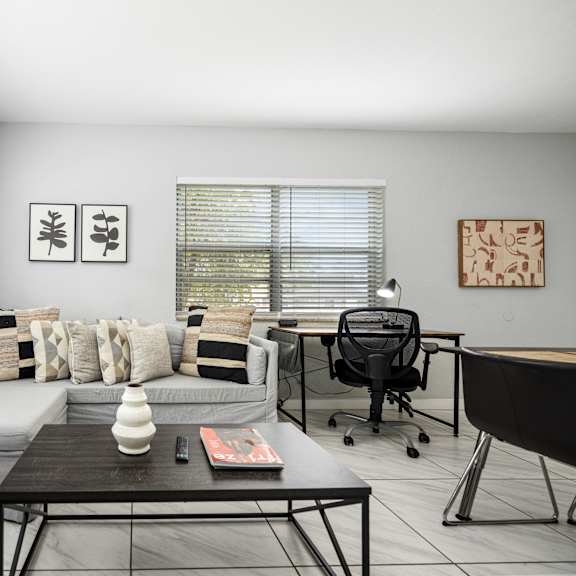 a modern living room with a grey couch, a black coffee table, and a black chair.
