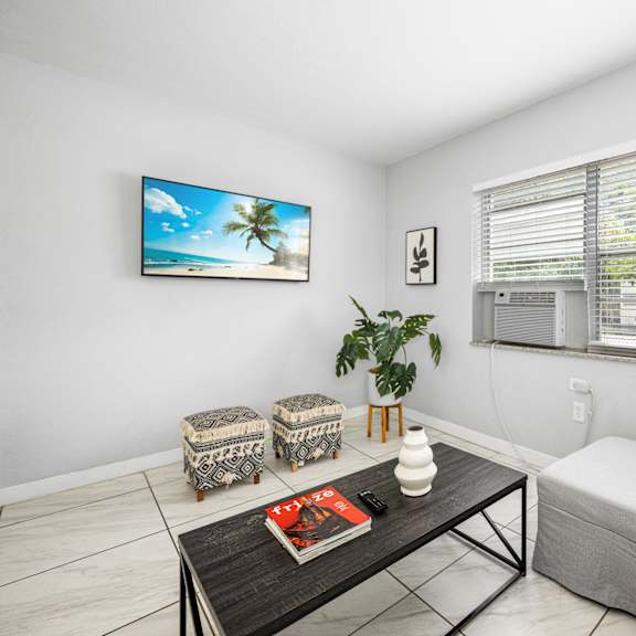 a living room with a flat screen tv mounted on the wall and a window with blinds.