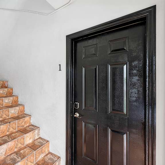 a black door with a glass window is on the right and a staircase with brown steps is on the left.