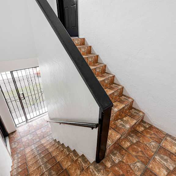 a staircase with a black railing and brown tiles.