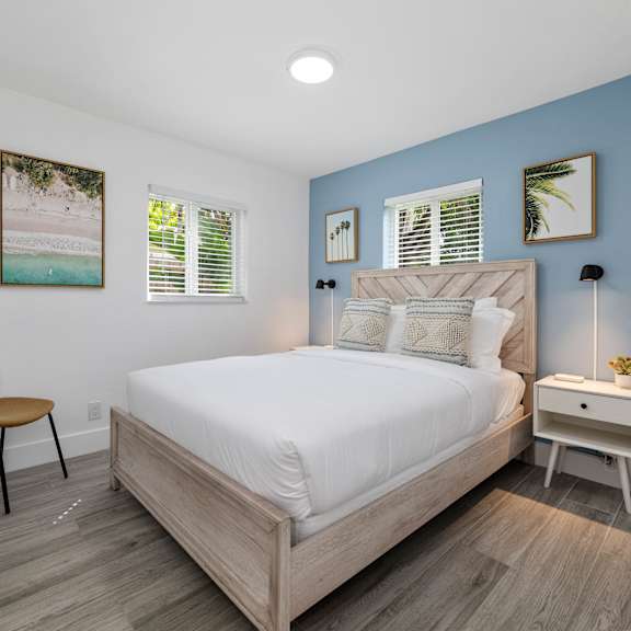 a bedroom with a bed, chair, and nightstand.