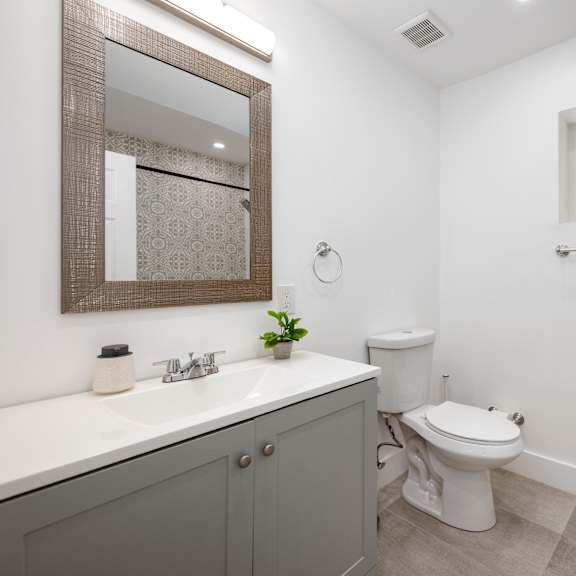a bathroom with a toilet, sink, and mirror.