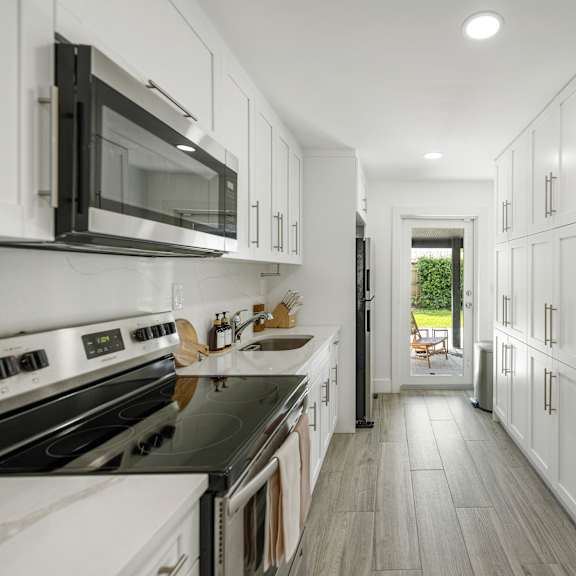 a modern kitchen with white cabinets and black appliances.