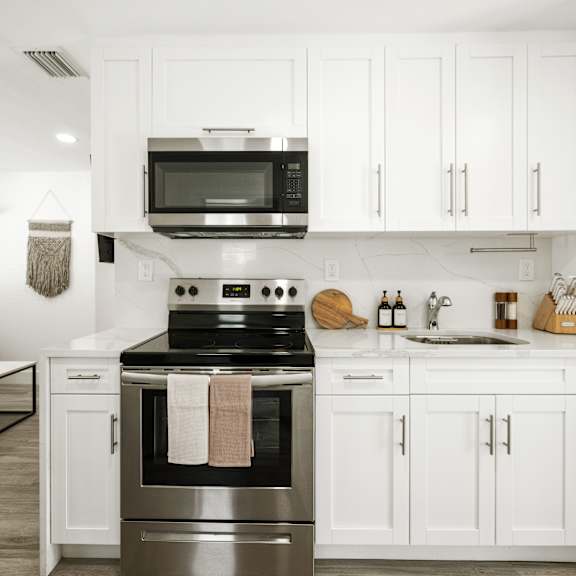 a modern kitchen with white cabinets and a stainless steel oven.
