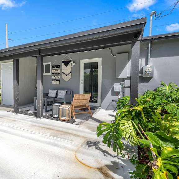a grey house with a patio and a chair.