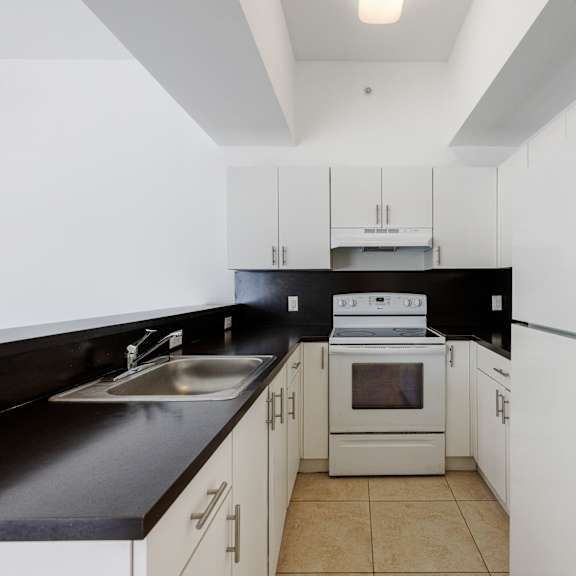 a kitchen with white cabinets and black countertops.