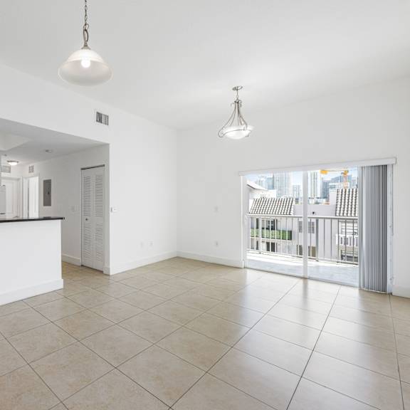 a spacious kitchen with a bar area and a large open floor plan leading to a balcony.