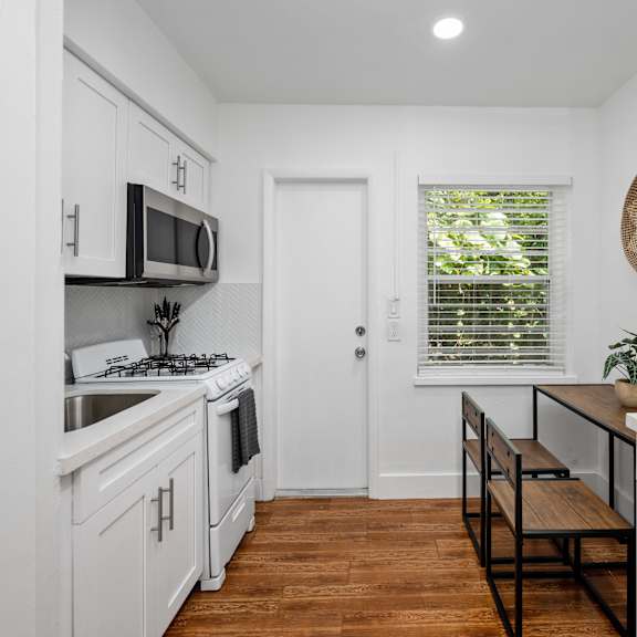 a kitchen with white cabinets and a wooden floor.