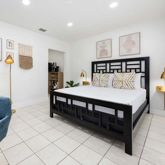 a bedroom with a bed, chair, and lamp.