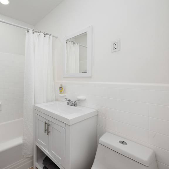 a white bathroom with a toilet, sink, and bathtub.