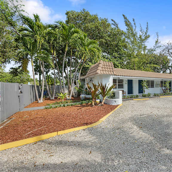 a house with a brown roof and a gravel driveway in front.