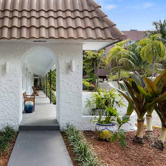 a white house with a brown roof and a white archway.