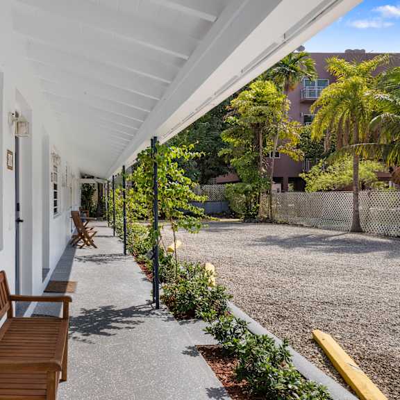 a long white covered walkway with benches and plants on the side.