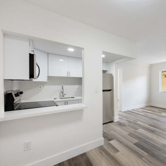 a kitchen with white cabinets and a wooden floor.