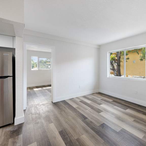 a kitchen with a refrigerator and a window with a view of trees.
