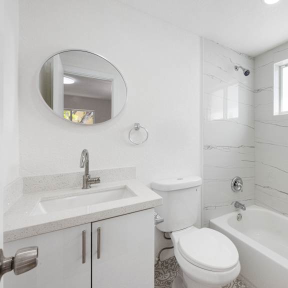 a white bathroom with a toilet, sink, and bathtub.