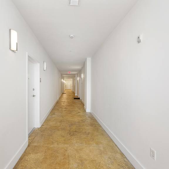 a long hallway with white walls and a light brown floor.