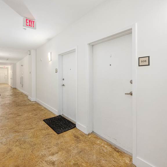 a hallway with a red exit sign above the door on the right.