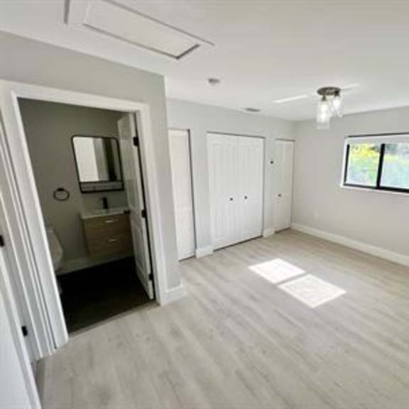 a room with a doorway leading to another room, a window, and a light fixture on the ceiling.