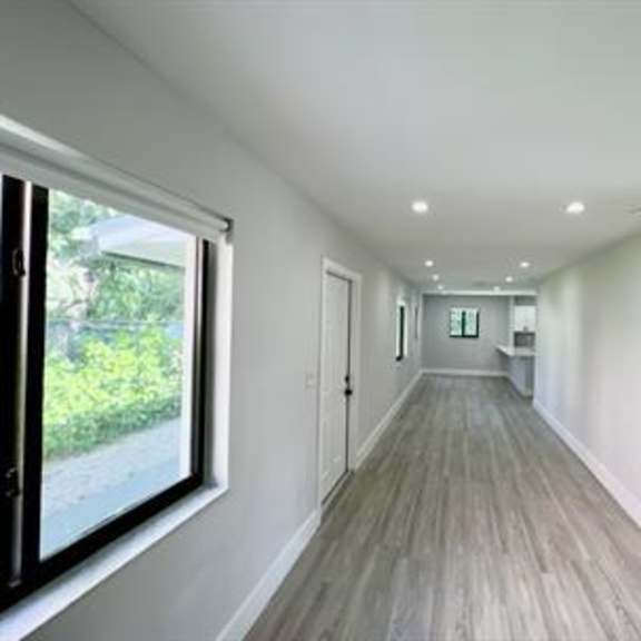 a long hallway with wood floors and white walls.