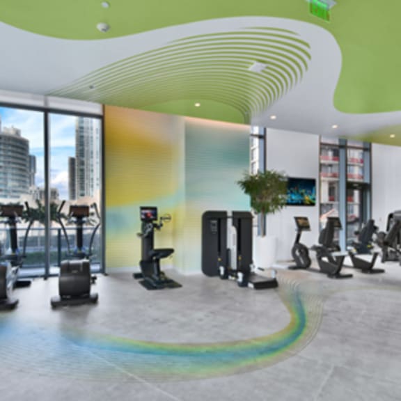 a gym with a variety of equipment including treadmills, stationary bikes, and weight machines.