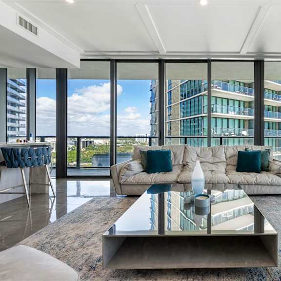 a modern living room with a glass table and a view of the city.
