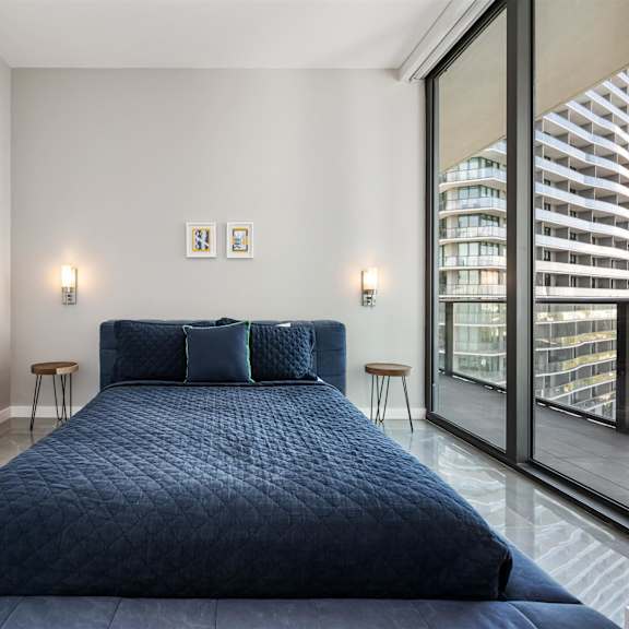 a bedroom with a large bed and a view of a building outside the window.