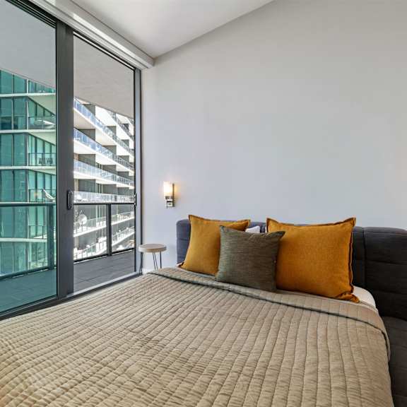 a bedroom with a large bed and a view of a building outside through the window.