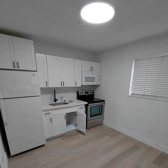 a kitchen with white cabinets and a wooden floor.