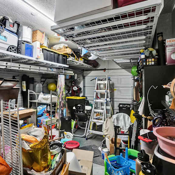 a cluttered garage with various items on shelves and the floor.