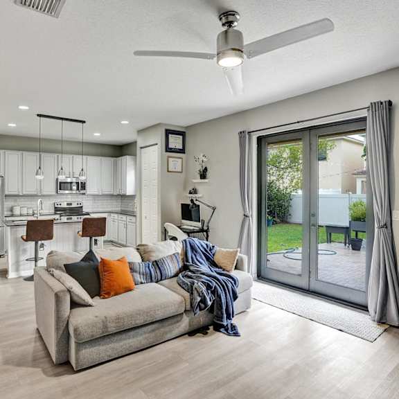 a modern living room with a grey couch and a ceiling fan.