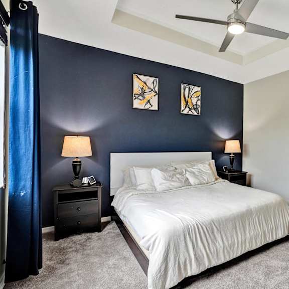 a bedroom with a bed, two nightstands with lamps, and a ceiling fan.