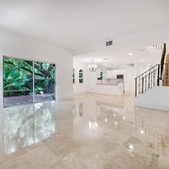 a spacious room with marble flooring and a staircase on the right side.