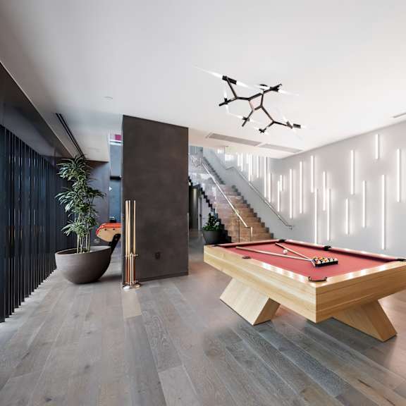 a pool table is in the middle of a room with a lighted wall behind it.