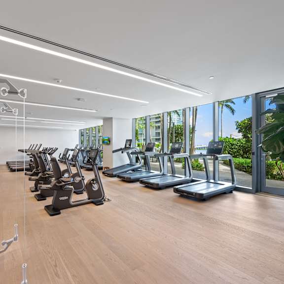 a gym with treadmills, exercise bikes, and a rowing machine.