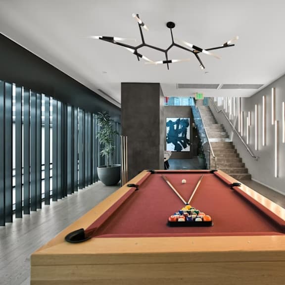 a pool table is in the middle of a room with a staircase in the background.
