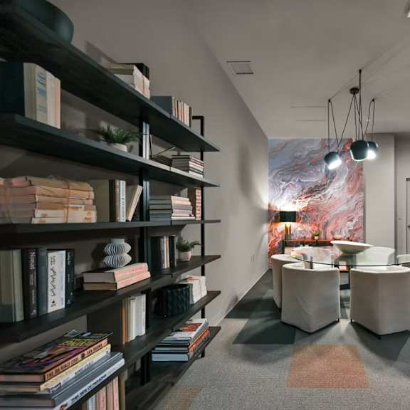 a room with a bookshelf, a table, and a chair.