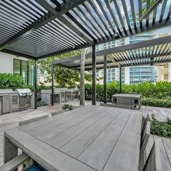 a wooden deck with a table and chairs under a roof.