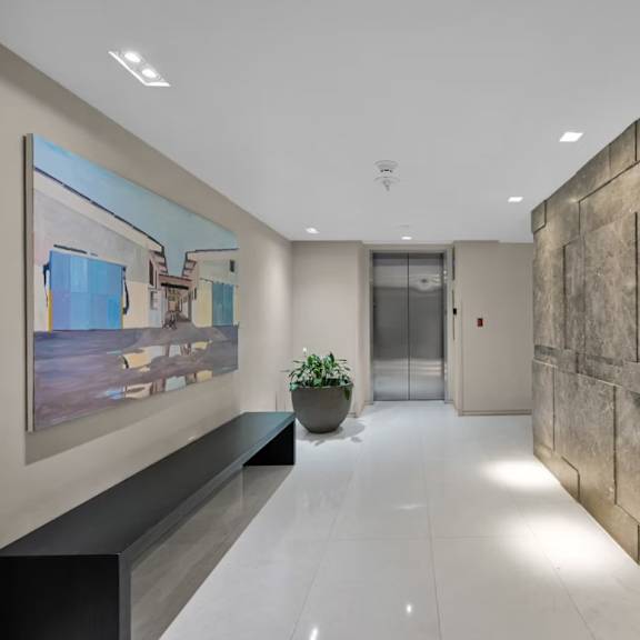 a hallway with a large painting on the wall and a plant on a bench.