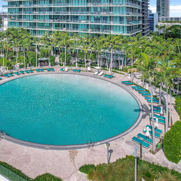 a large outdoor swimming pool surrounded by palm trees and lounge chairs.