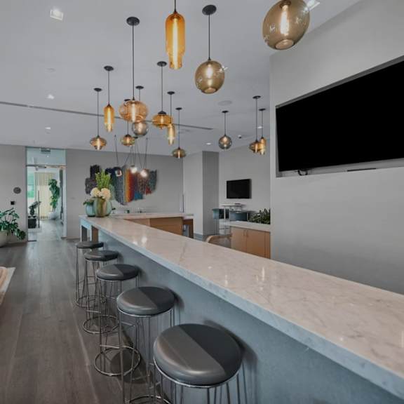 a modern bar area with a long counter and stools.