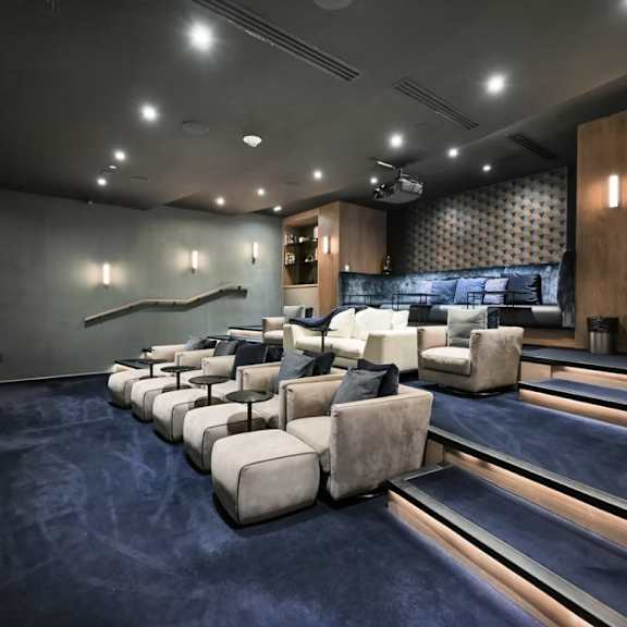 a modern home theater with a row of white chairs facing a screen.