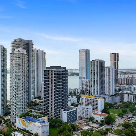 a cityscape with tall buildings and a body of water in the background.
