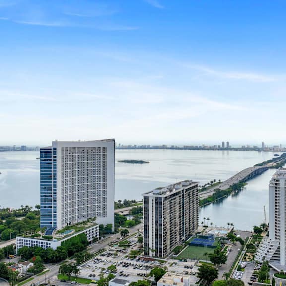 a cityscape with a large body of water in the foreground and a bridge in the distance.