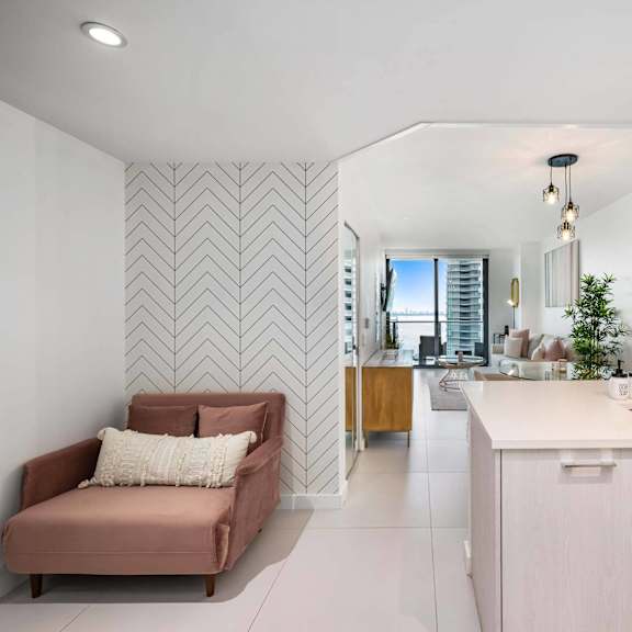 a modern kitchen with a pink couch and a herringbone wallpaper.
